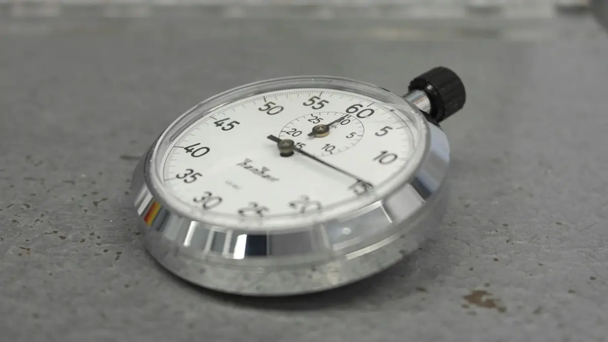 A silver stopwatch lying on a grey surface