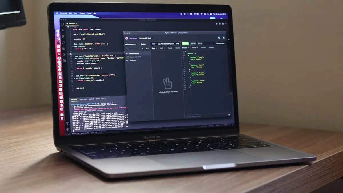 A laptop on a wooden desk showing code and a terminal